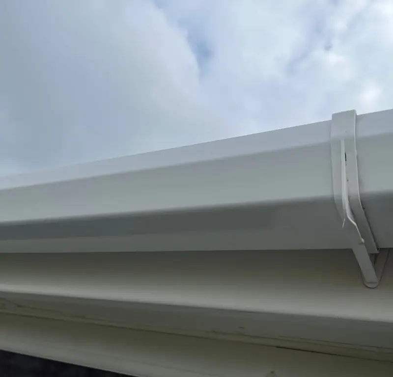 The same white gutter after cleaning, with the grass and moss gone